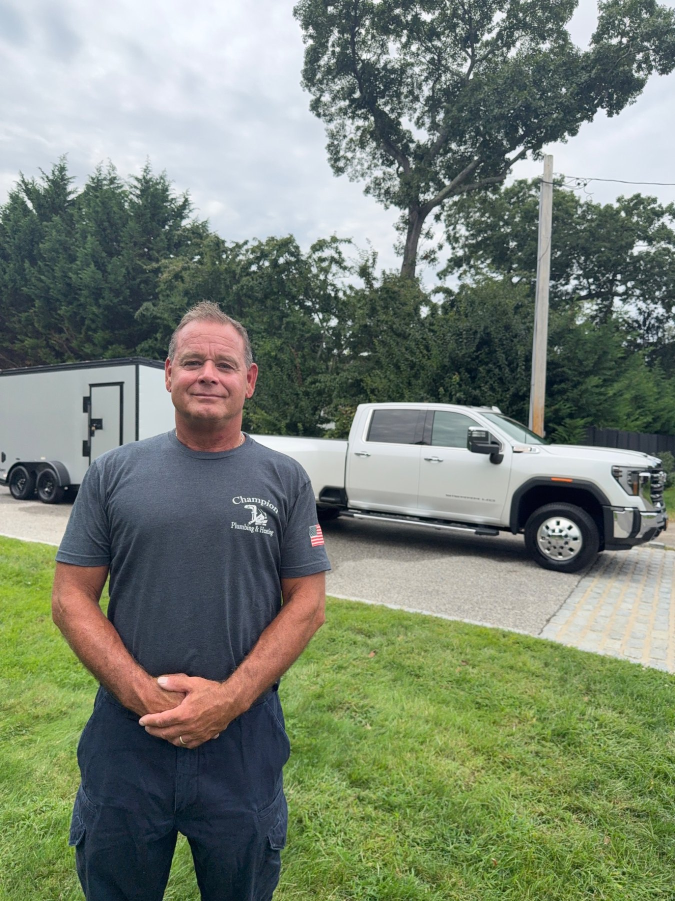 Champion Plumbing & Heating owner standing in front of his truck and trailer